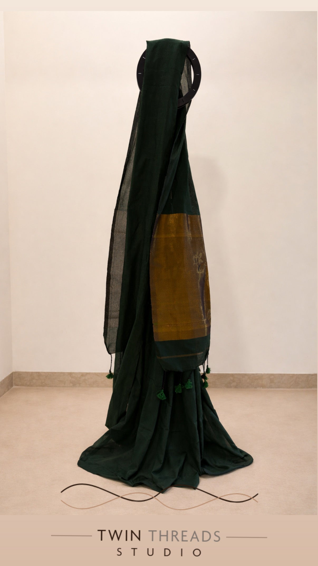 Dark green saree with a brown patch on a white background, branded 'Twin Threads Studio'.