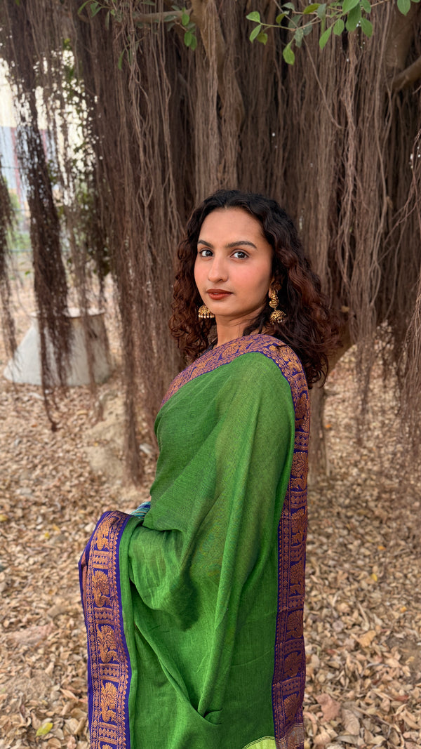 Woman in a green saree standing in front of a tree with a natural background